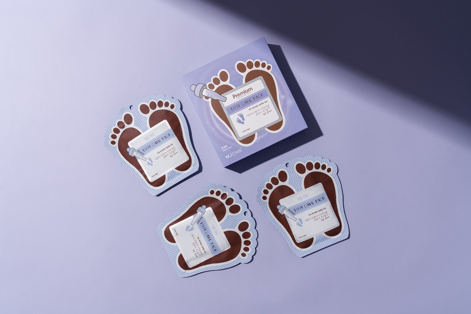 Masques pieds Foot Care Pack disposés avec packaging dans une mise en scène élégante