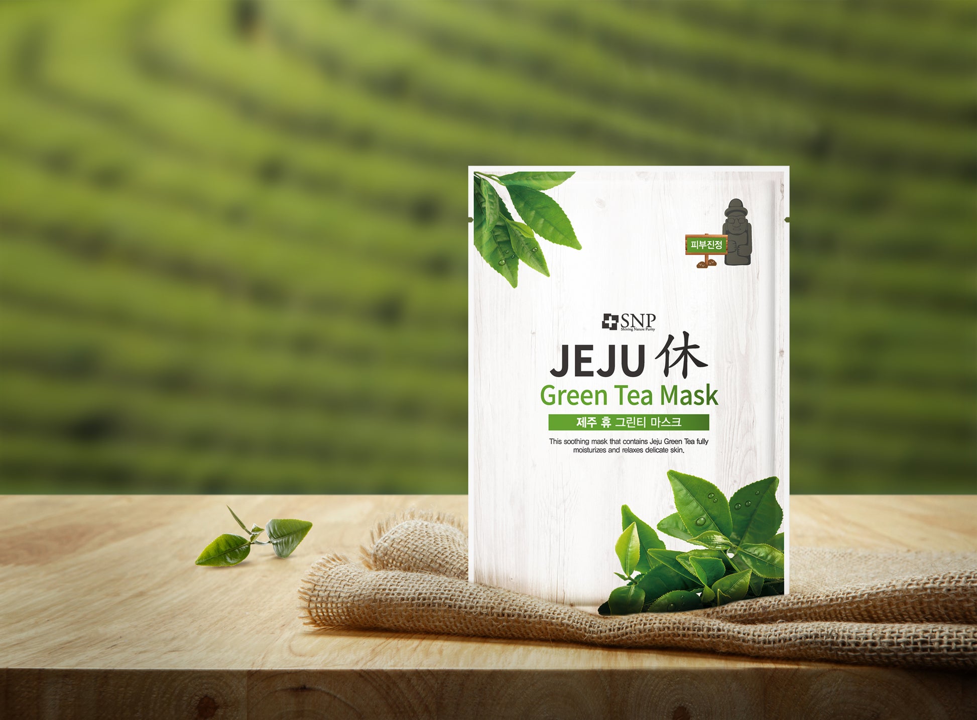 Masque visage au thé vert Jeju posé sur table en bois avec plantation de thé en arrière-plan